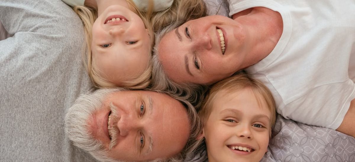 A joyful multigenerational family lying down and smiling together, displaying warmth and affection.
