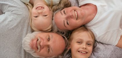 A joyful multigenerational family lying down and smiling together, displaying warmth and affection.