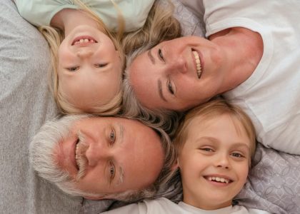 A joyful multigenerational family lying down and smiling together, displaying warmth and affection.